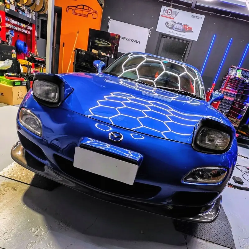 Blue Mazda RX-7 FD under the workshop hex lighting
